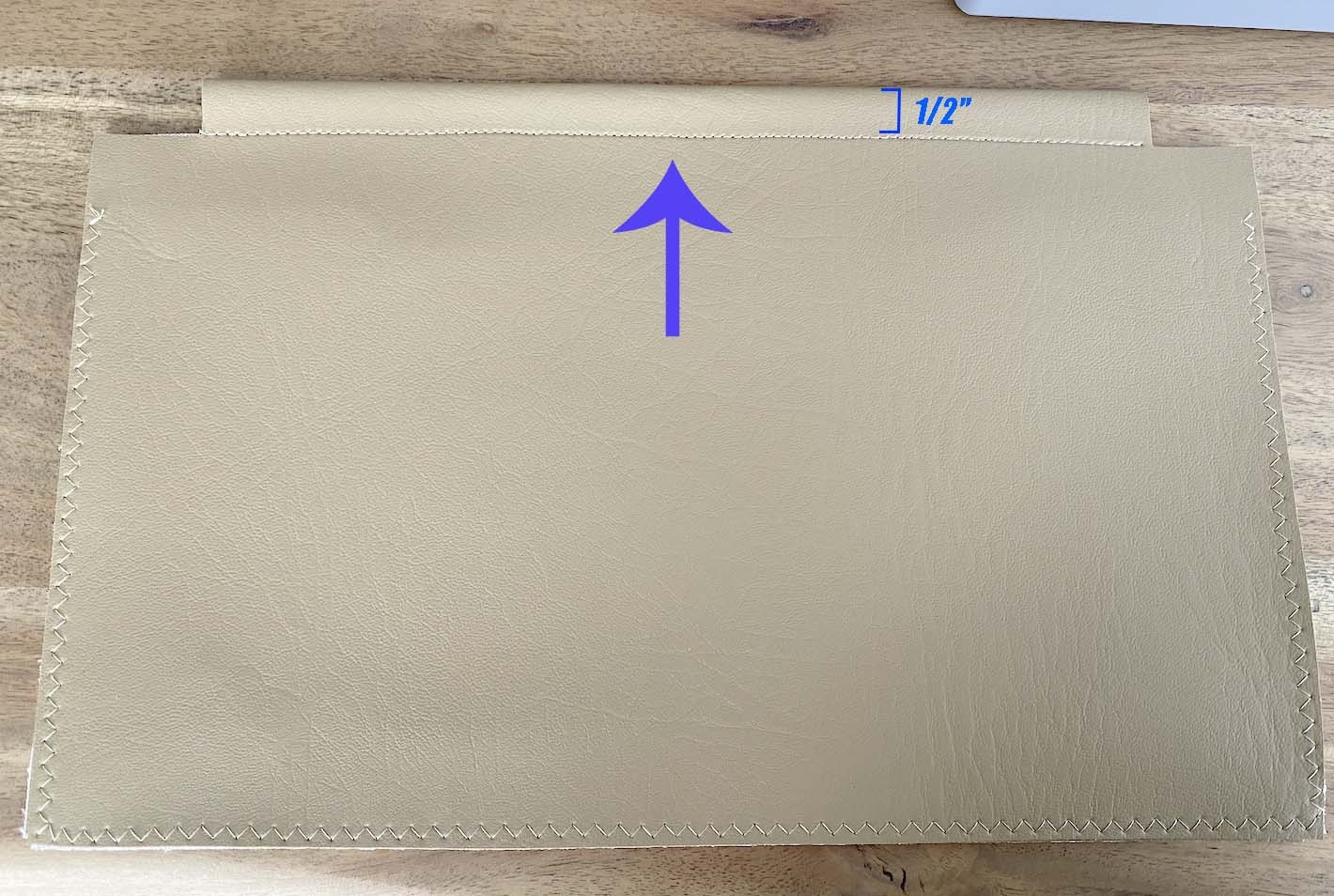 Blue arrow points out a sewn line in leather bag and a box bracket indicates the size of height, 1/2".