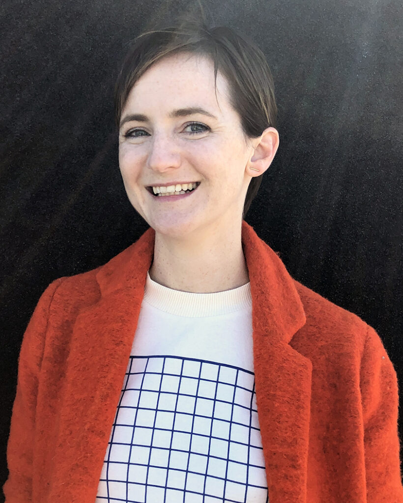 Woman with short hair in a red sweater smiling at the camera.